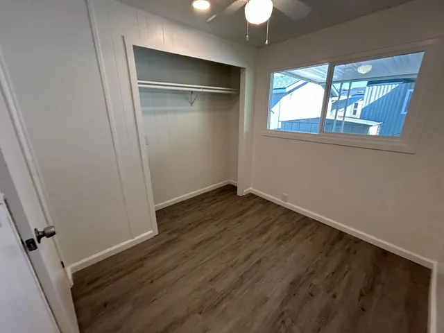 an empty room with wooden floor fan and windows