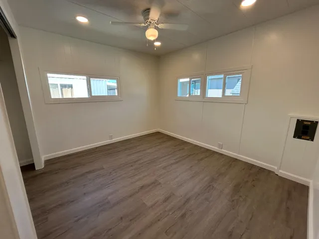 an empty room with wooden floor fan and window