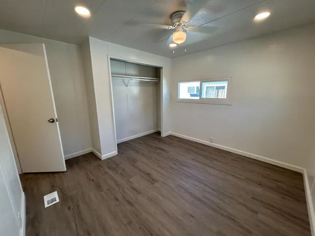 an empty room with wooden floor and ceiling fan