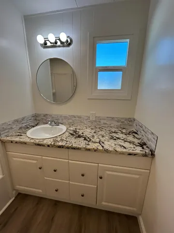 a bathroom with a granite countertop sink a mirror and shower