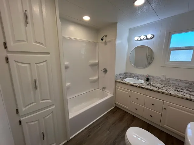 a bathroom with a granite countertop toilet sink and mirror