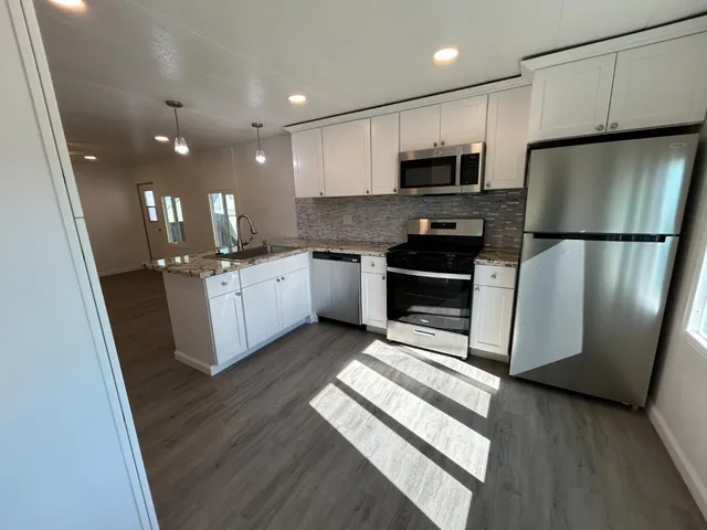 a kitchen with stainless steel appliances granite countertop a refrigerator a stove a sink and a microwave