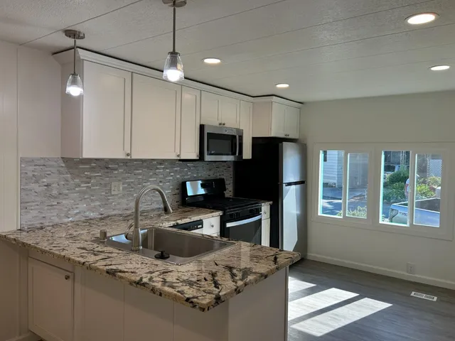 a kitchen with kitchen island granite countertop a sink refrigerator and microwave