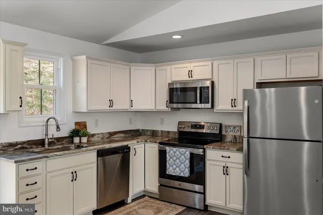 a kitchen with stainless steel appliances granite countertop white cabinets and window