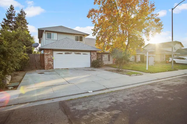 a view of a house with a yard and large tree