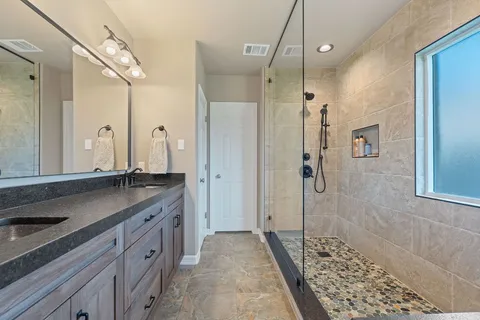 a bathroom with a granite countertop sink mirror and shower