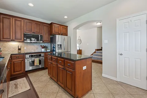 a kitchen with stainless steel appliances granite countertop a stove top oven a sink dishwasher and a refrigerator with wooden cabinets