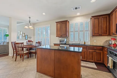 a large kitchen with kitchen island granite countertop a sink a stove counter space and dining table