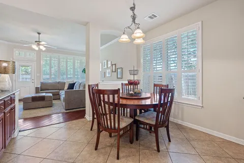 a view of a dining room with furniture a chandelier and large windows