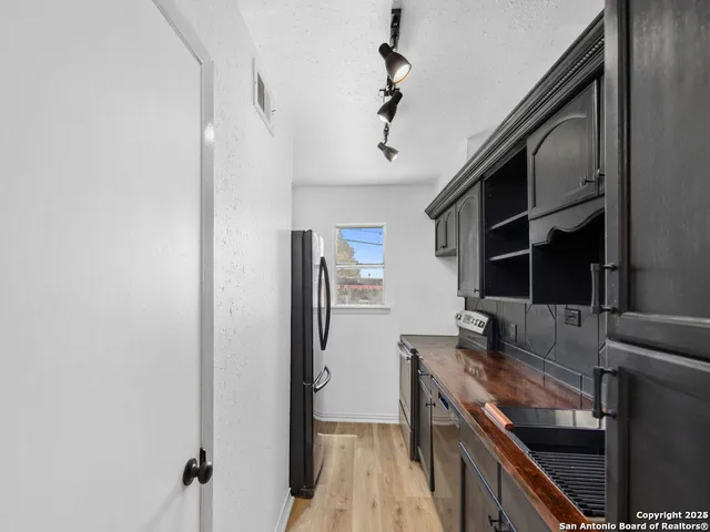 a kitchen with stainless steel appliances granite countertop a refrigerator a stove and a sink with wooden floor