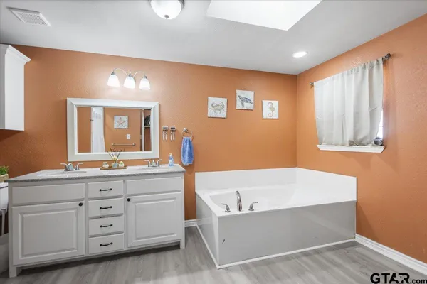a bathroom with a tub sink and mirror
