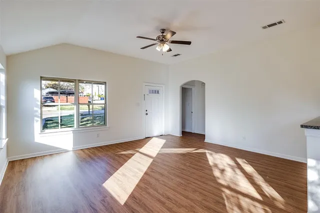 a view of an empty room with wooden floor and a window