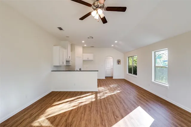 a view of an empty room with window and wooden floor