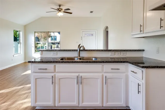 a kitchen with granite countertop white cabinets and a sink