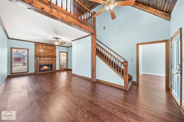 an empty room with wooden floor fireplace and windows