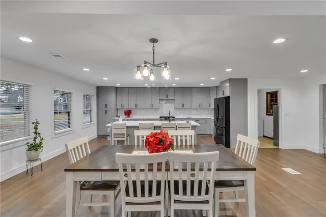 a kitchen with stainless steel appliances granite countertop a stove a dining table and chairs with wooden floor
