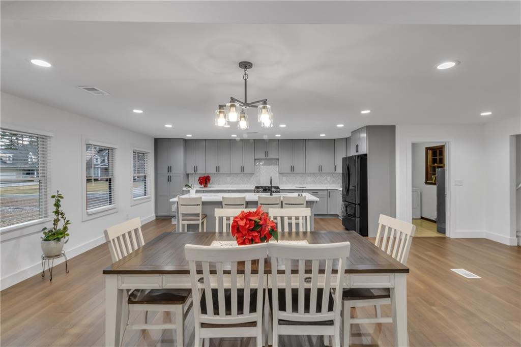 a kitchen with stainless steel appliances granite countertop a stove a dining table and chairs with wooden floor