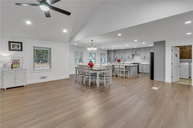 a view of a dining room and livingroom with furniture wooden floor a chandelier