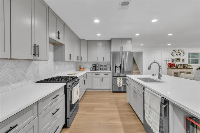 a kitchen with stainless steel appliances kitchen island granite countertop a dining table chairs and white cabinets