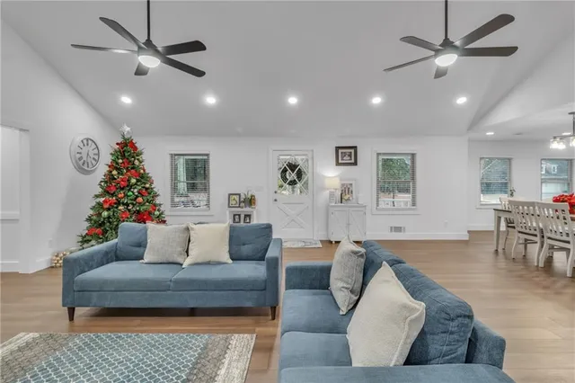 a living room with furniture and kitchen view with wooden floor