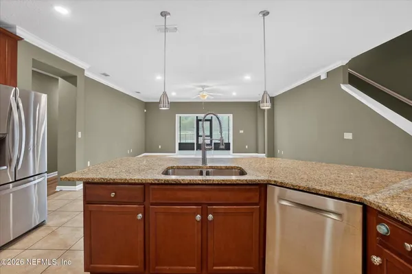 a kitchen with granite countertop kitchen island stainless steel appliances sink and refrigerator