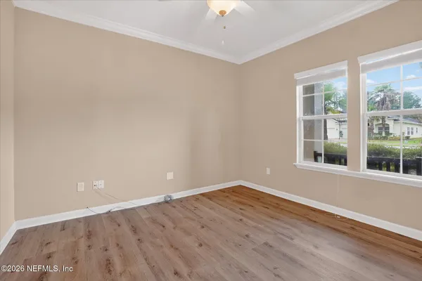 a view of an empty room with wooden floor and a ceiling fan