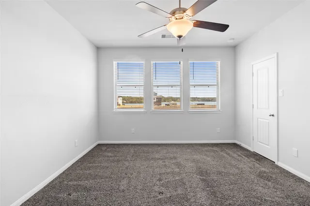 an empty room with windows and fan