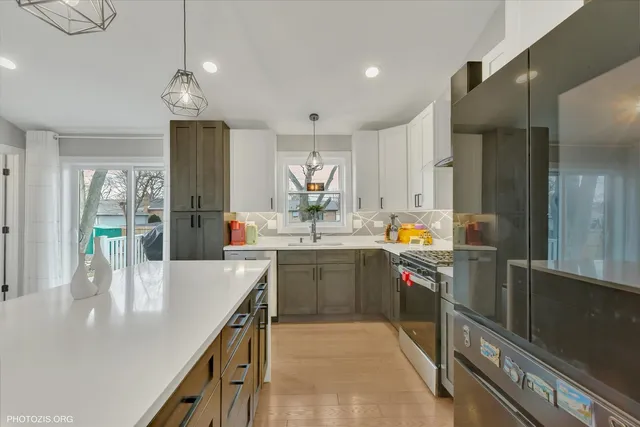 a kitchen with stainless steel appliances granite countertop a refrigerator a sink a stove and a refrigerator