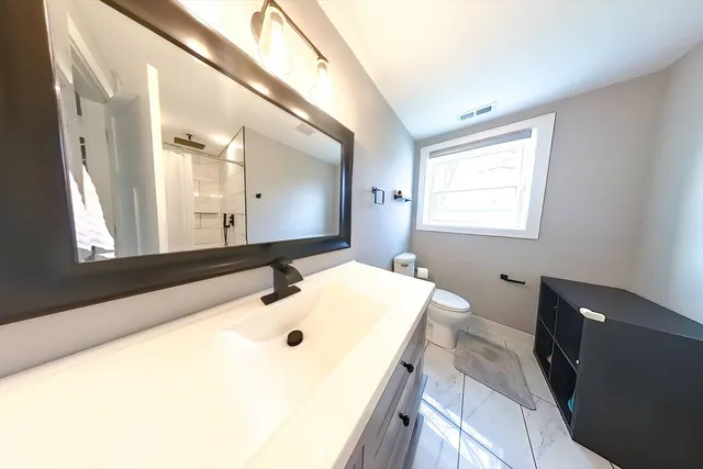 a view of an empty room with wooden floor and mirror