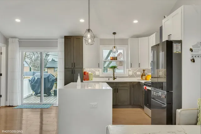 a kitchen with stainless steel appliances kitchen island granite countertop a stove top oven a sink a dining table and chairs with wooden floor