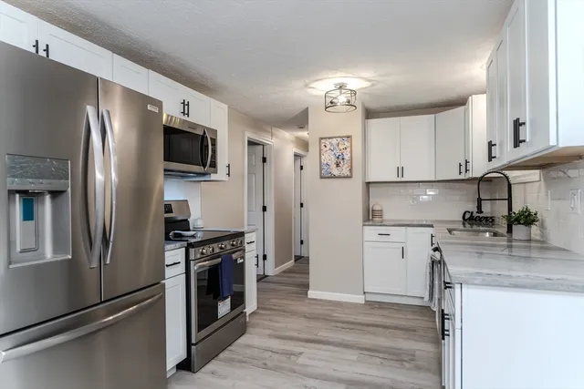 a kitchen with kitchen island granite countertop stainless steel appliances cabinets a sink and a counter space