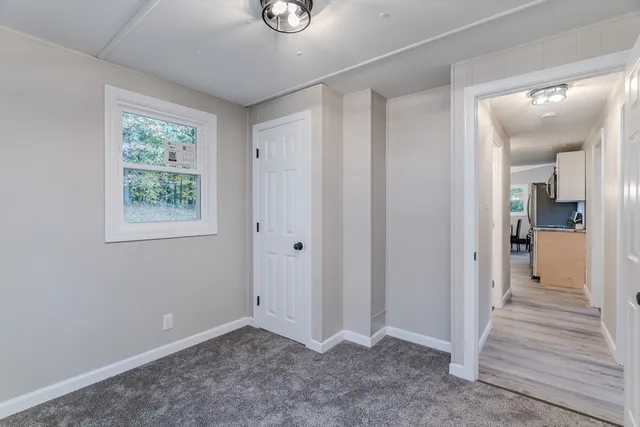 a view of a hallway with wooden floor and a bathroom