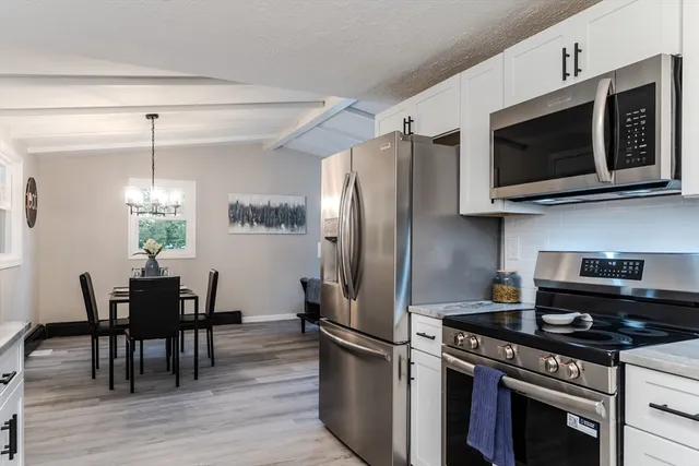 a kitchen with stainless steel appliances a kitchen island a stove a microwave a dining table and chairs