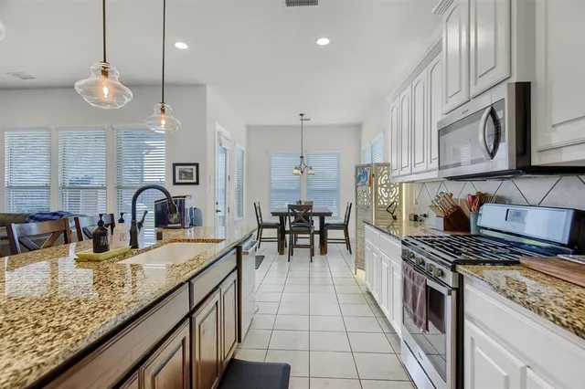 a kitchen with granite countertop a stove a sink a dining table and chairs