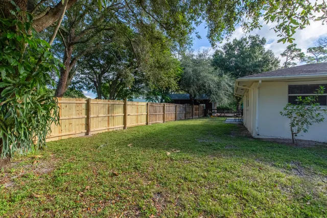 a view of a backyard with table and chairs and wooden fence