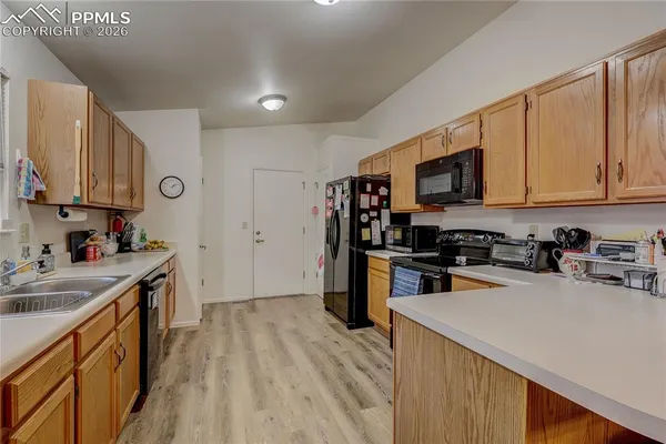 a kitchen with stainless steel appliances a stove top oven a sink a refrigerator white cabinets and wooden floor