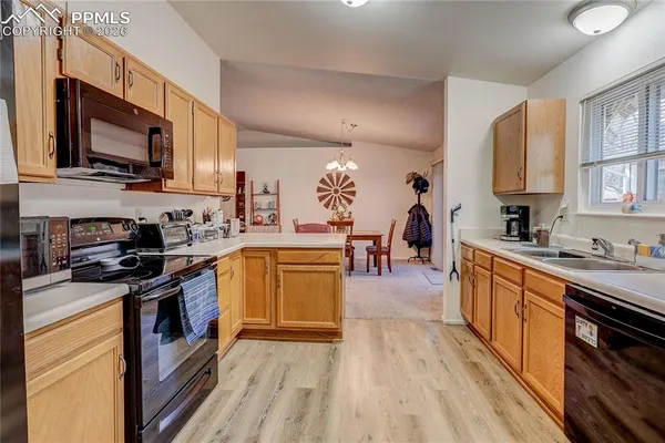 a kitchen with stainless steel appliances granite countertop a stove top oven a sink dishwasher and a microwave oven with wooden floor