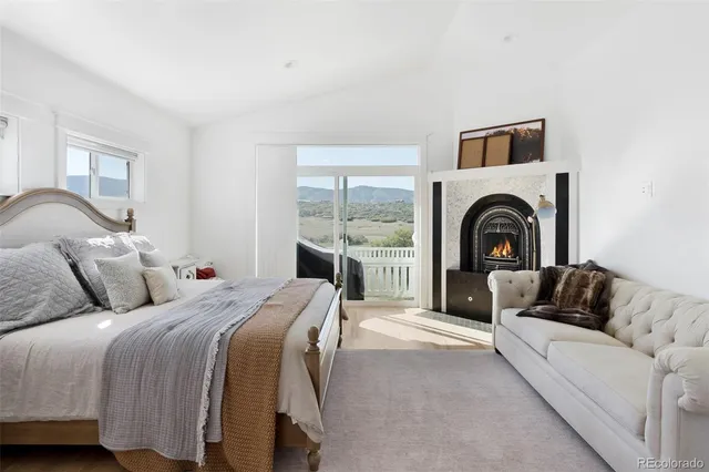 a living room with a bed a fireplace and a large window