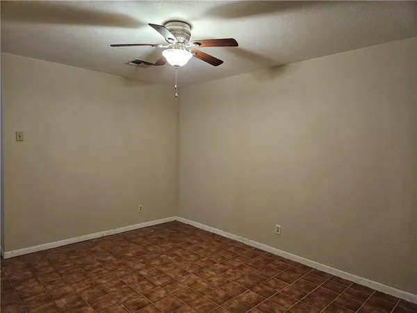 an empty room with a chandelier fan and a ceiling fan