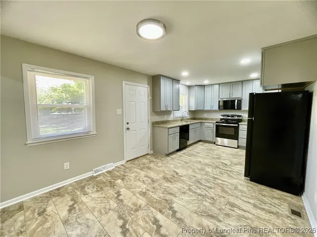 a kitchen with granite countertop a refrigerator and a stove top oven