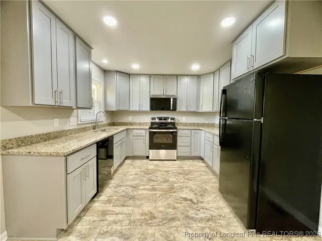 a kitchen with granite countertop a refrigerator and a sink
