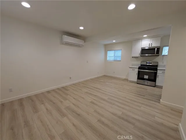 an empty room with wooden floor and stainless steel appliances