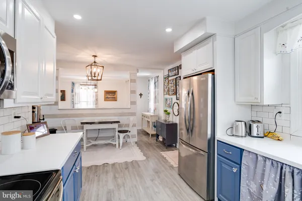 a kitchen with stainless steel appliances a stove a sink and a dining table with wooden floor