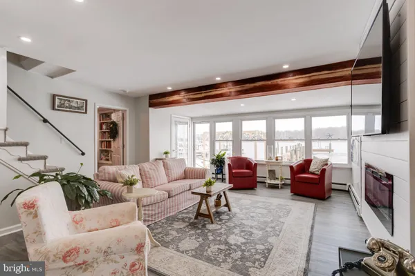 a living room with furniture a flat screen tv and floor to ceiling windows