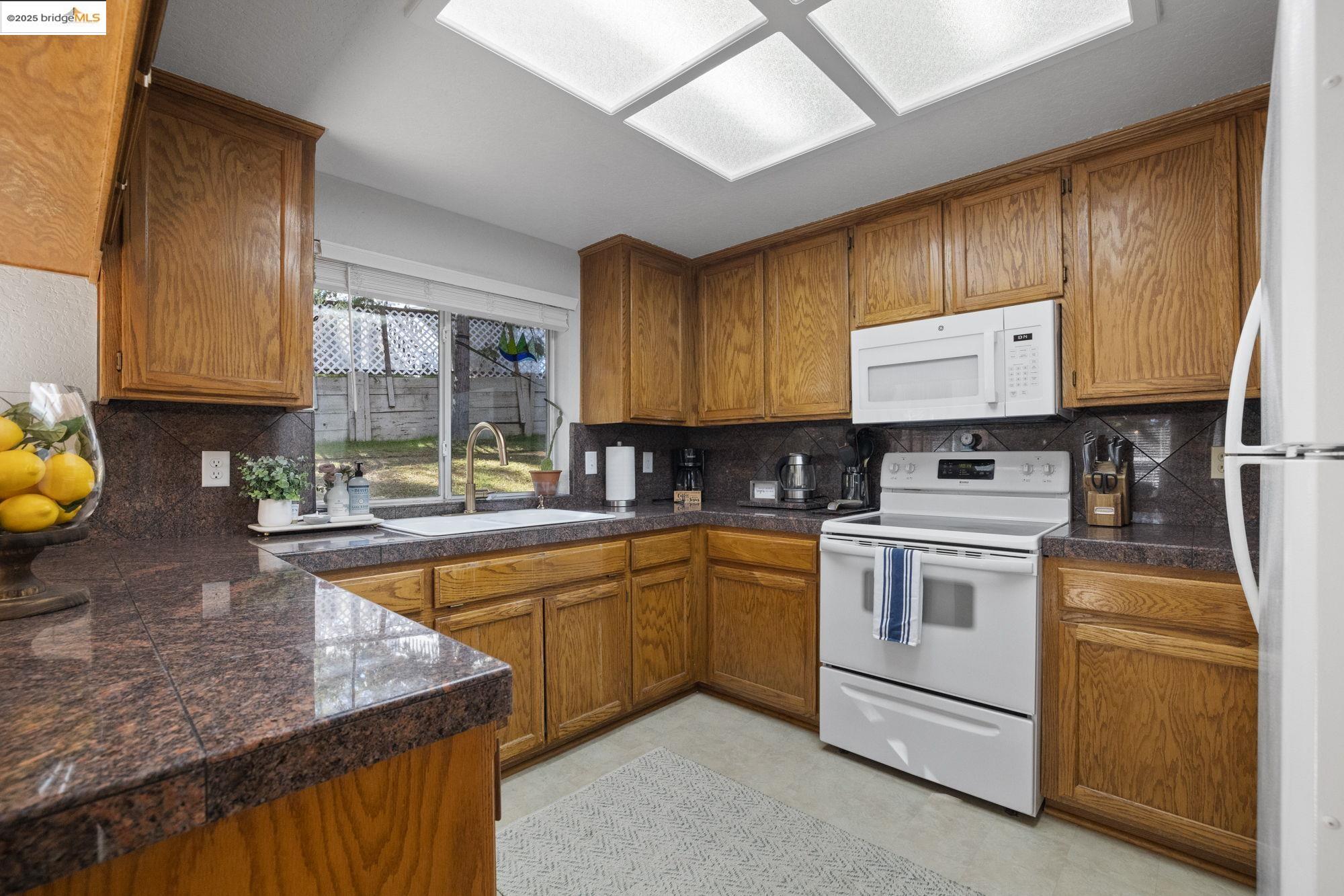 12080 Breckenridge Road Groveland, CA 95321 - Photo 13 of 48 a kitchen with stainless steel appliances granite countertop wooden cabinets a stove a sink and a microwave