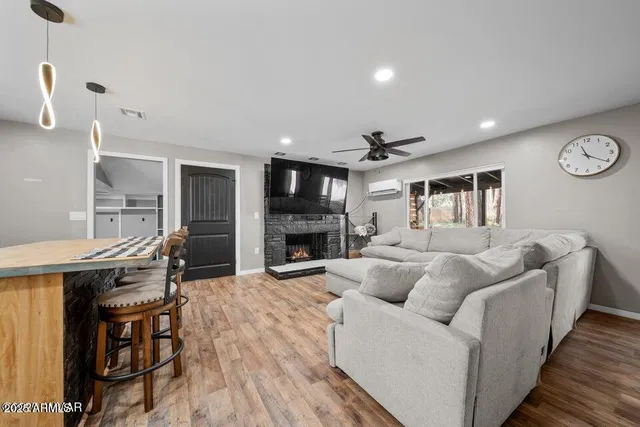 a kitchen with stainless steel appliances granite countertop a kitchen island a stove a refrigerator a sink a dining table and chairs with wooden floor