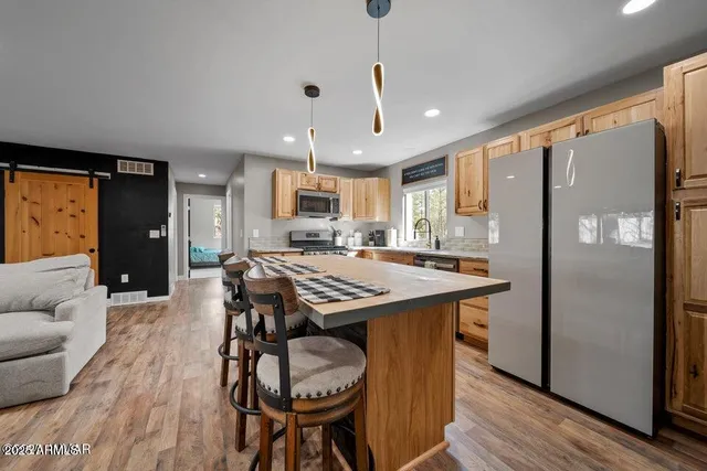 a kitchen with stainless steel appliances granite countertop a stove top oven a sink dishwasher a refrigerator and a microwave