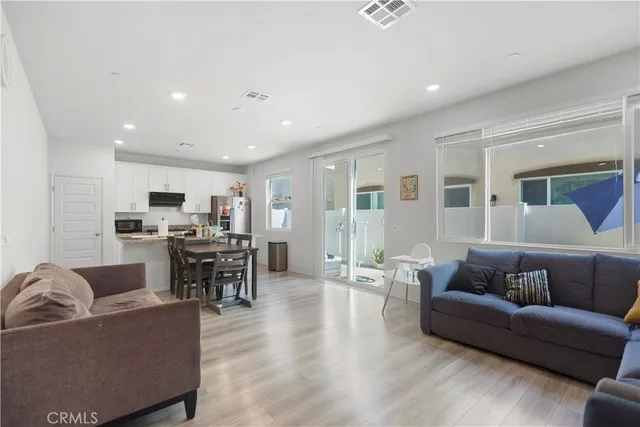 a living room with furniture kitchen view and a wooden floor