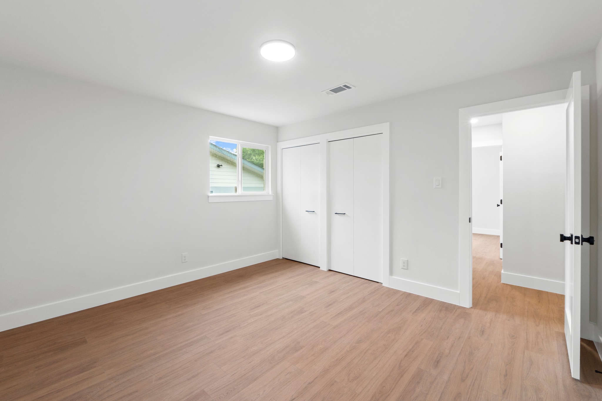 1608 Springer Lane Austin, TX 78758 - Photo 22 of 35 Bright room featuring wood-finish flooring, a contemporary ceiling light fixture, white walls, and white trim