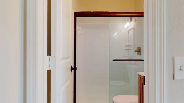 a view of a hallway with wooden floor and a bathroom